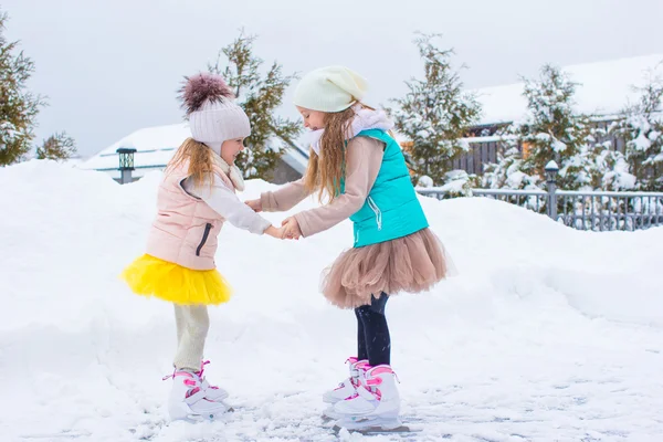 Очаровательные маленькие девочки катаются на катке на открытом воздухе в зимний снежный день — стоковое фото