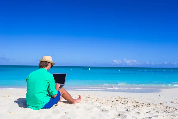 Młody człowiek działa na laptopie w tropikalnej plaży — Zdjęcie stockowe