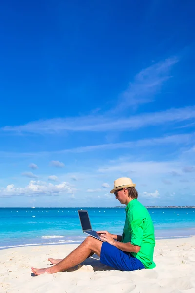 Młody człowiek działa na laptopie w tropikalnej plaży — Zdjęcie stockowe