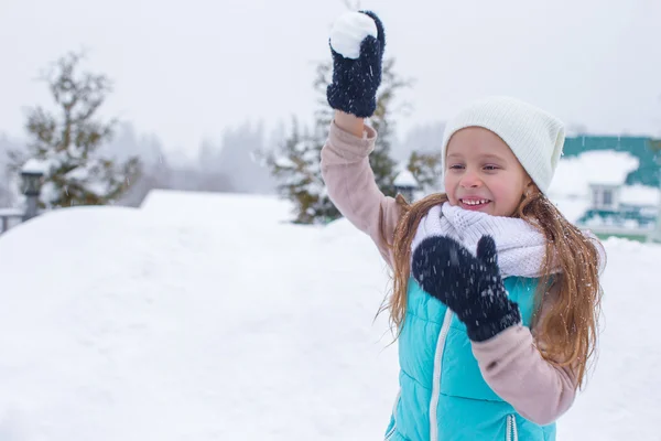 Niña hermosa jugando bolas de nieve en el día de invierno nevado —  Fotos de Stock