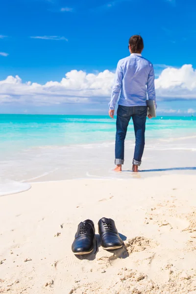 Hombre joven con portátil durante las vacaciones en la playa tropical — Foto de Stock