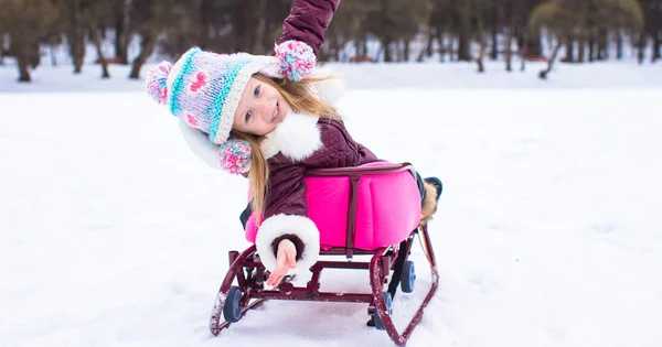 Adorable little happy girl sledding in winter snowy day — Stock Photo, Image