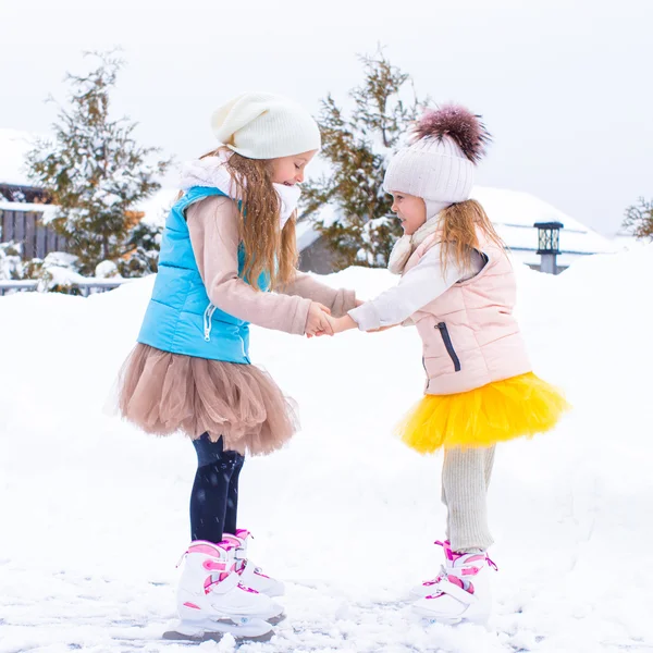 Adorables niñas patinando en pista de hielo en el día de nieve de invierno —  Fotos de Stock