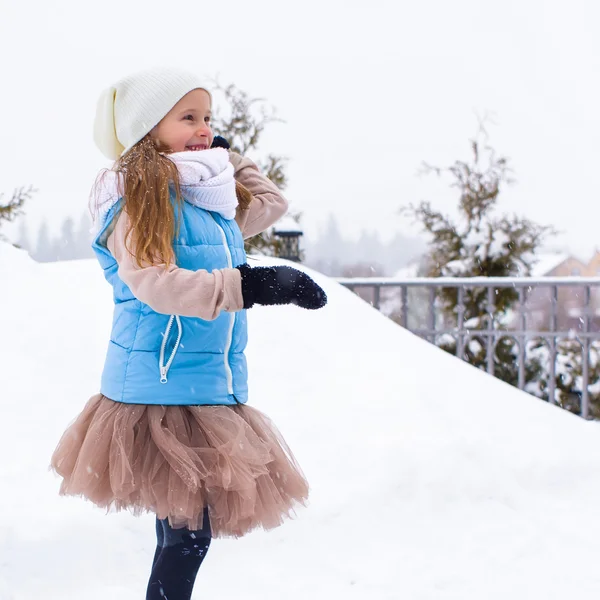 Entzückendes kleines Mädchen, das im Winter draußen Schneebälle spielt — Stockfoto