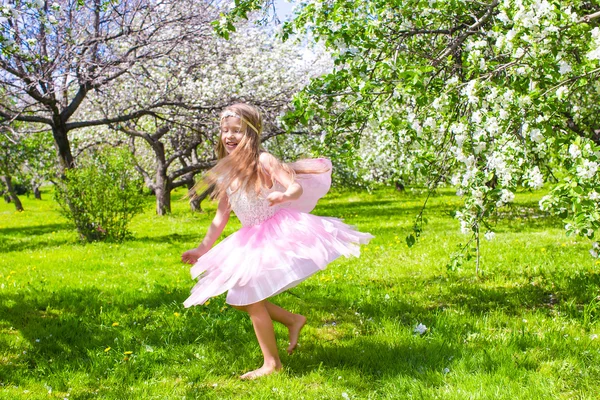 Bedårande liten flicka har roligt i blommande apple träd trädgård — Stockfoto