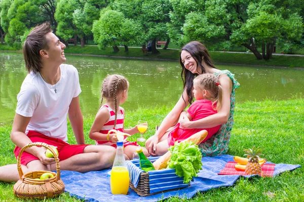 Familia joven feliz picnic al aire libre cerca del lago —  Fotos de Stock