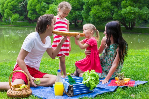 Happy young family picnicking outdoors — Stock Photo, Image