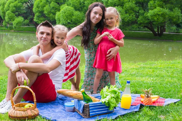 Glückliche Eltern und zwei Kinder beim Picknicken im Freien — Stockfoto