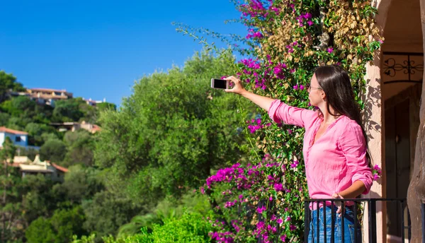 Joven hermosa mujer tomar fotos en su teléfono en el balcón — Foto de Stock