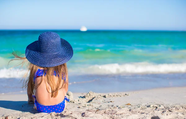 Entzückendes kleines Mädchen mit großem blauen Strohhut am weißen Strand — Stockfoto