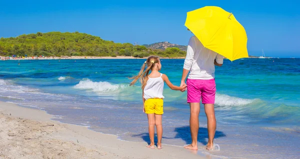 Küçük kız ve genç Baba sarı şemsiye ile beyaz Beach — Stok fotoğraf