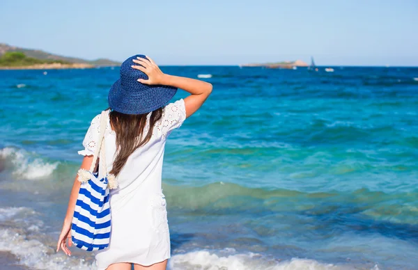 Mujer joven con sombrero de paja y bolsa de rayas azules en la playa tropical — Foto de Stock