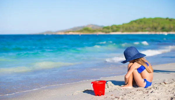 Adorable little girl in big blue straw hat at white beach — Stock Photo, Image