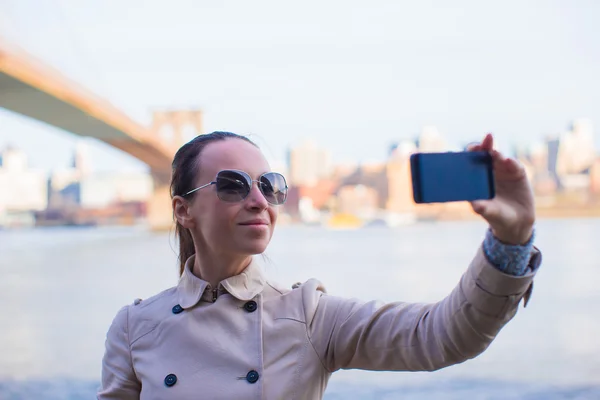 Young woman photographing herself on background of Brooklyn Bridge — ストック写真