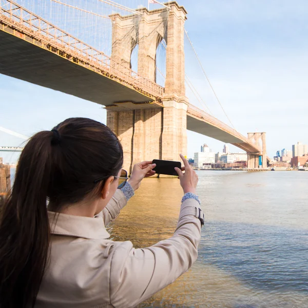 Young girl photographed the Brooklyn Bridge — стокове фото