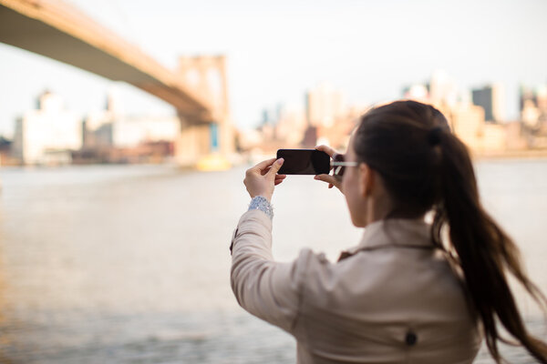 Young happy girl photographed the Brooklyn Bridge