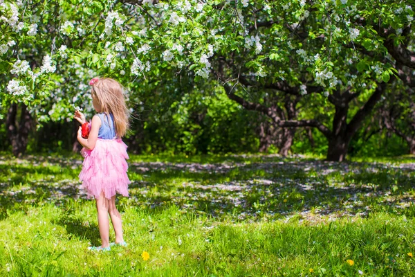 Adorable niña se divierten en el jardín de manzanos en flor a mayo —  Fotos de Stock