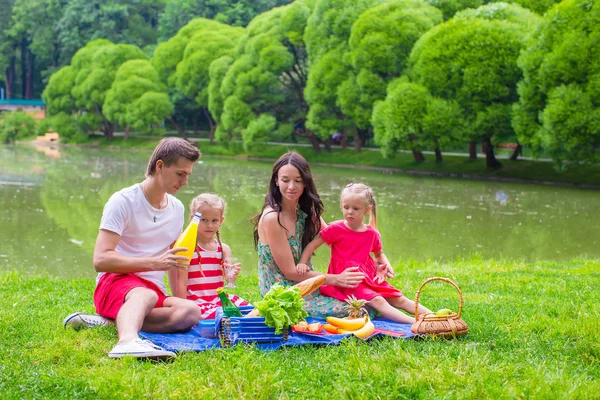 Happy parents and two kids picnicking outdoors — Stock Photo, Image