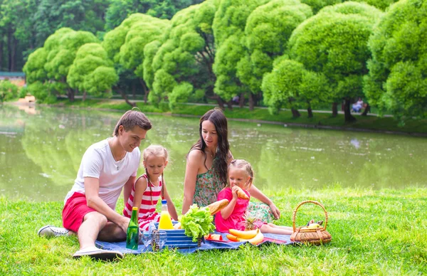 Happy parents and two kids picnicking outdoors — Stock Photo, Image