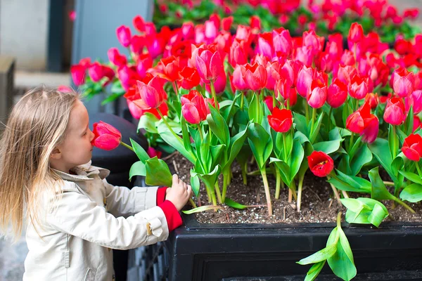 Liten bedårande flicka nära röda blommor i New York gator — Stockfoto