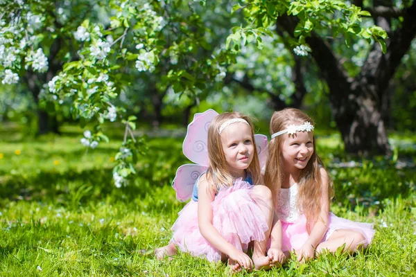 Adorables niñas en el jardín de manzanos en flor en el día de primavera —  Fotos de Stock