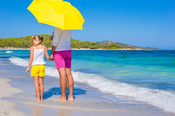 Küçük kız ve genç Baba sarı şemsiye ile beyaz Beach — Stok fotoğraf