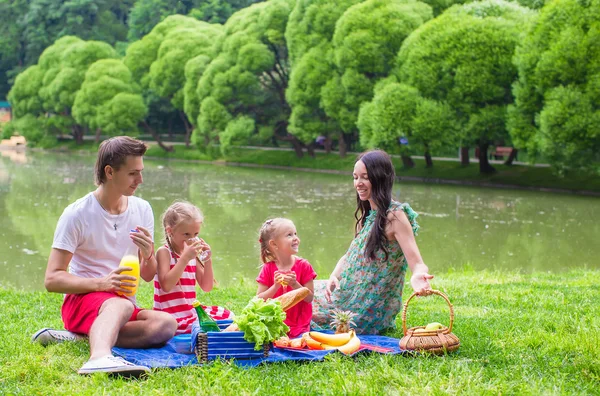 Familia joven feliz picnic al aire libre cerca del lago — Foto de Stock