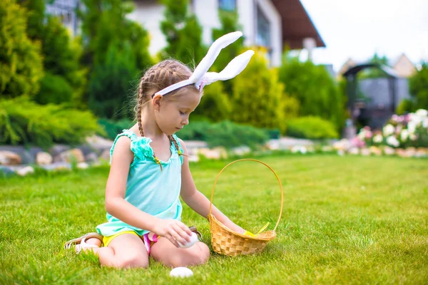 Adorable little girl wearing bunny ears holding basket with Easter eggs — Stock Photo, Image