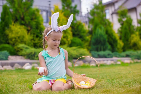 Entzückendes kleines Mädchen mit Hasenohren, die einen Korb mit Ostereiern halten — Stockfoto