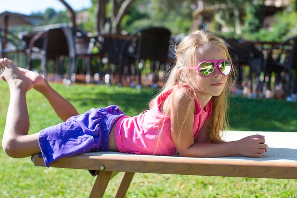 Adorable petite fille sur chaise longue de plage en plein air — Photo