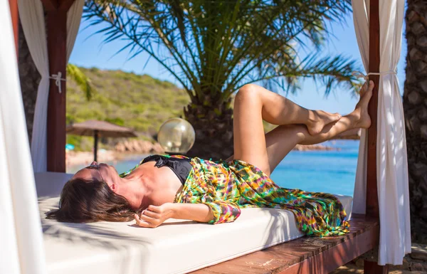 Young beautiful woman relaxing on beach bed during tropical vacation — Stock Photo, Image