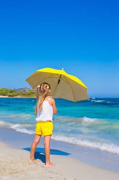 Little adorable girl with big yellow umbrella on tropical beach — Stock Photo, Image