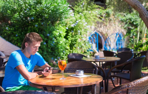 Mladý muž v venkovní kavárny na mobil — Stock fotografie
