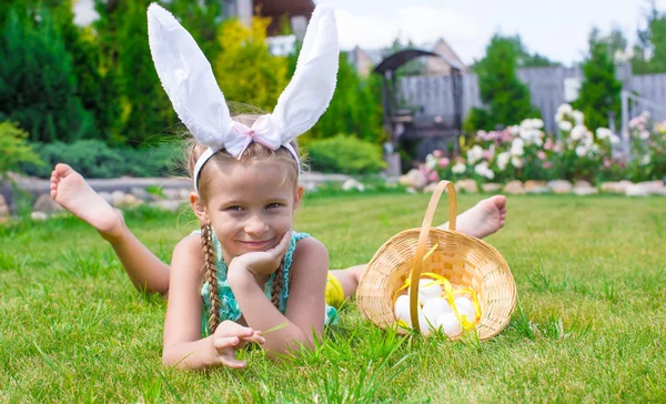 Adorable little girl wearing bunny ears holding basket with Easter eggs — Stock Photo, Image