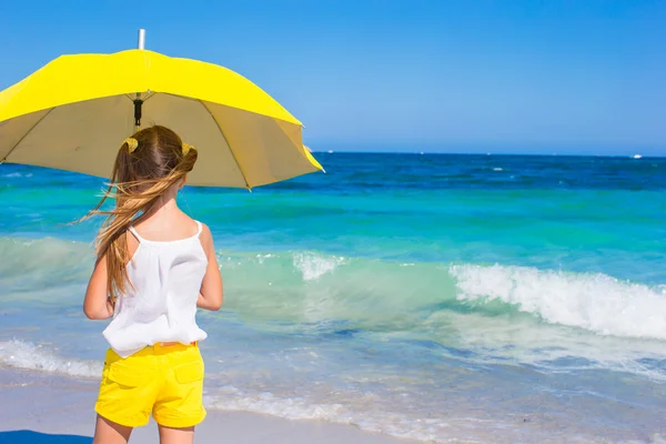 Pequena menina adorável com grande guarda-chuva amarelo na praia tropical — Fotografia de Stock