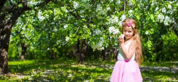 Glad liten bedårande flicka i blommande apple träd trädgård — Stockfoto
