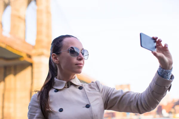 Jovem mulher tomando selfie no fundo da ponte de Brooklyn — Fotografia de Stock