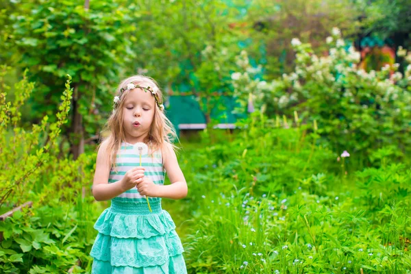 Adorable little girl blowing a dandelion in the garden — Stock Photo, Image