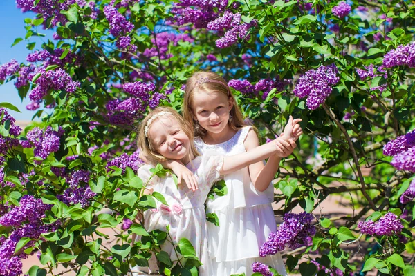 Little adorable girls enjoying beautiful day in blooming garden — Stock Photo, Image