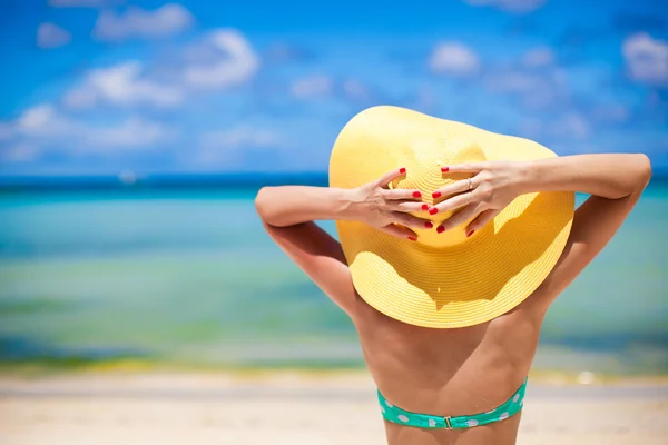 Mooie vrouw in geel hoed op wit tropisch strand — Stockfoto