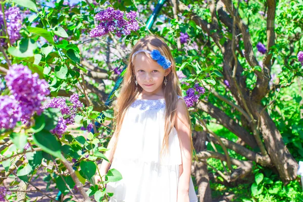 Bedårande liten flicka i blommande lila blomsterträdgård — Stockfoto