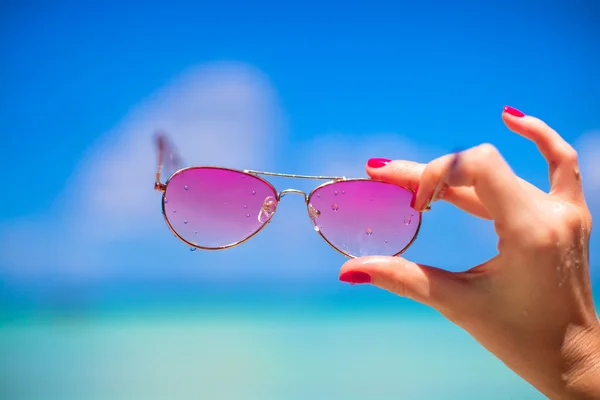 Primer plano de gafas de sol de color rosa en la playa tropical — Foto de Stock