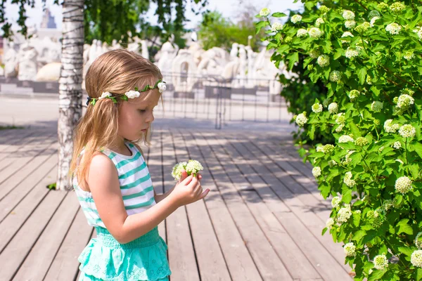 Niña adorable cerca de flores blancas en el jardín —  Fotos de Stock