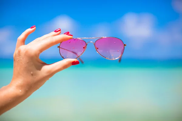 Primer plano de gafas de sol de color rosa en la playa tropical —  Fotos de Stock
