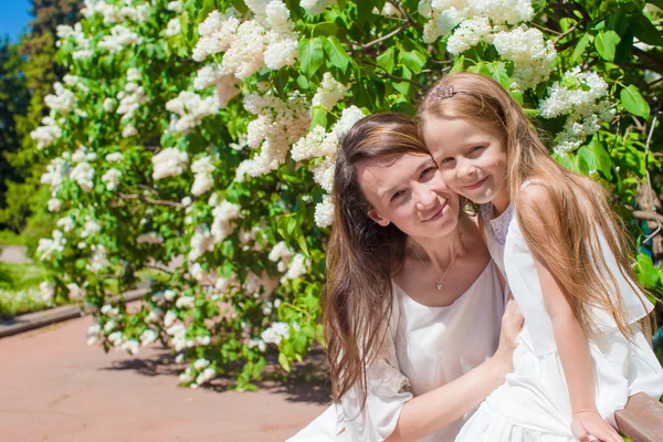 Happy mother and adorable girl enjoying warm day in lush garden — Stock Photo, Image