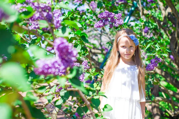 Adorable little girl in blossoming lilac flower garden — Stock Photo, Image