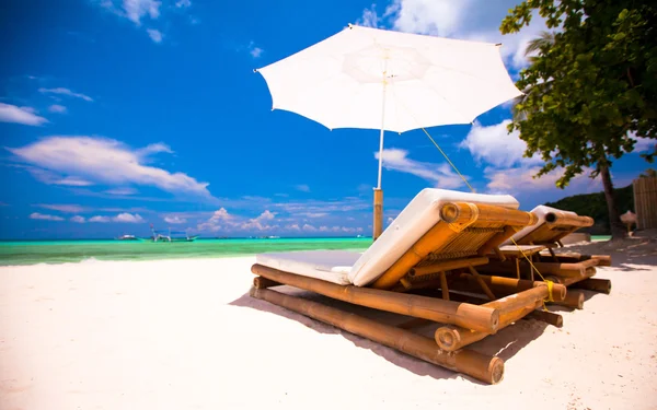ビーチチェアとエキゾチックな熱帯白い砂浜で傘 — ストック写真