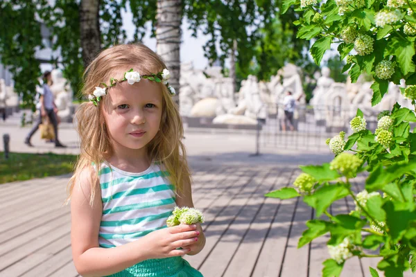 Kleines entzückendes Mädchen in der Nähe weißer Blumen im Garten — Stockfoto