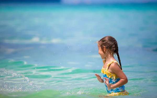 Little happy girl at swimsuit having fun in clear sea — Stock Photo, Image
