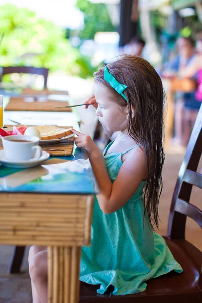 Rozkošná holčička se snídaní v venkovní kavárně — Stock fotografie